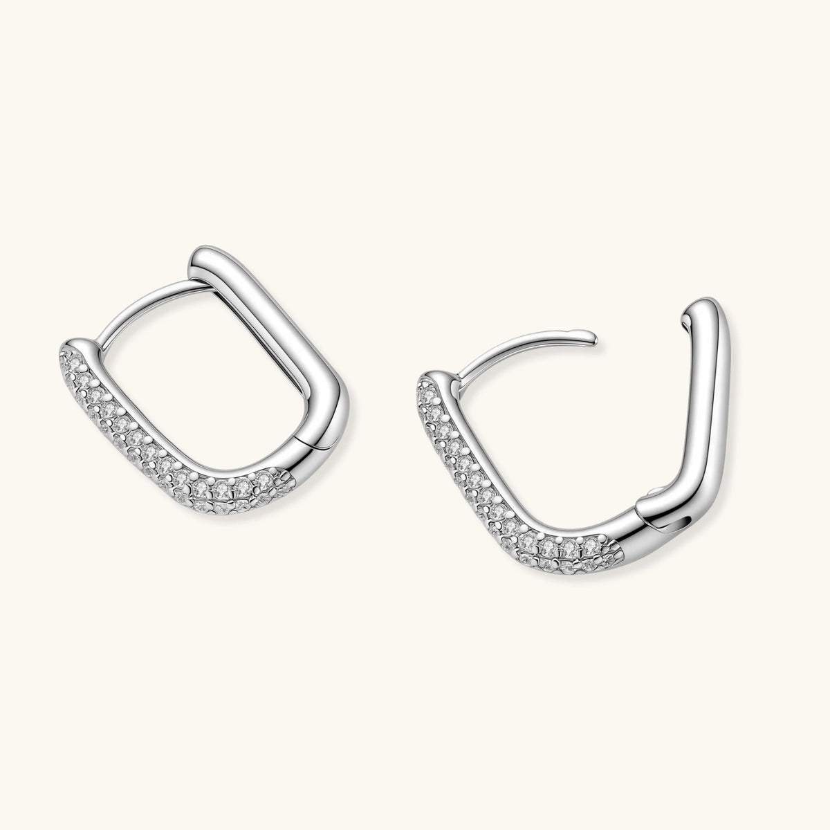 Close-up of platinum-plated sterling silver huggie hoops with pavé crystal setting on white background.